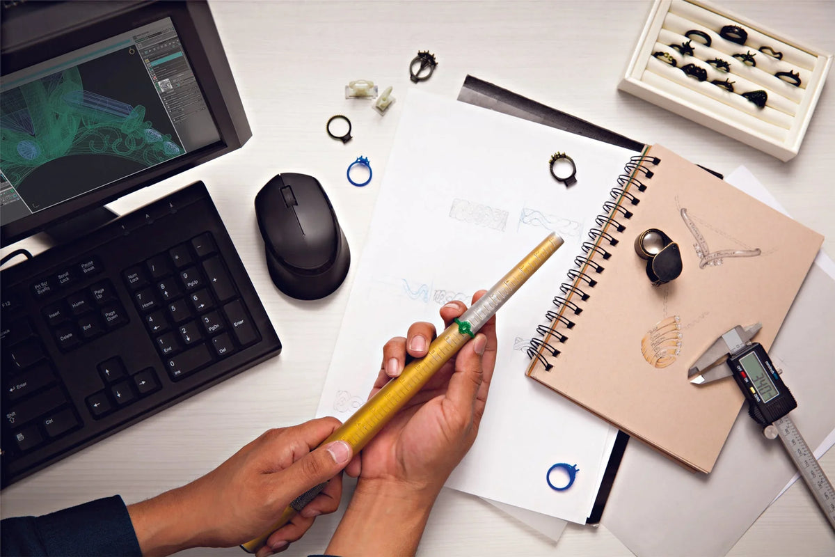 Jeweler desk with ring sketches, CAD design and wax ring models for a custom engagement ring