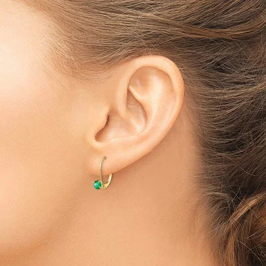 Woman wearing gold hoop earring with green gemstone, fine jewelry close-up