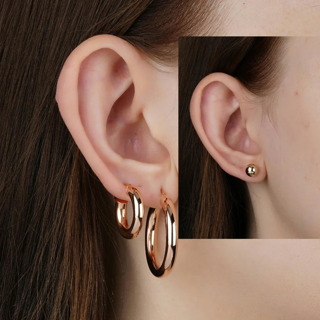 Close-up of woman wearing polished gold hoop earrings and gold stud earring