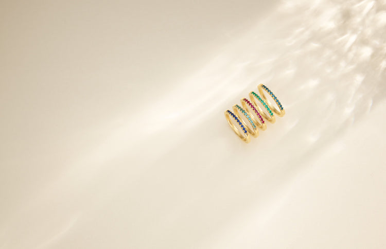 Stackable gold birthstone rings in warm sunlight – Picasso Gold & Diamond Chicago