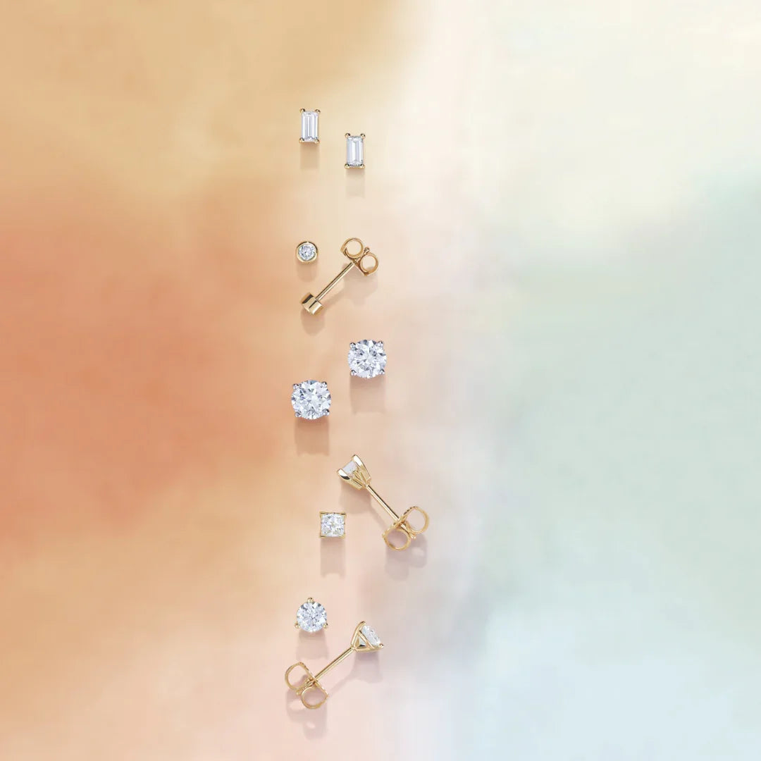 Assorted diamond stud earrings and gold settings displayed on a soft gradient background