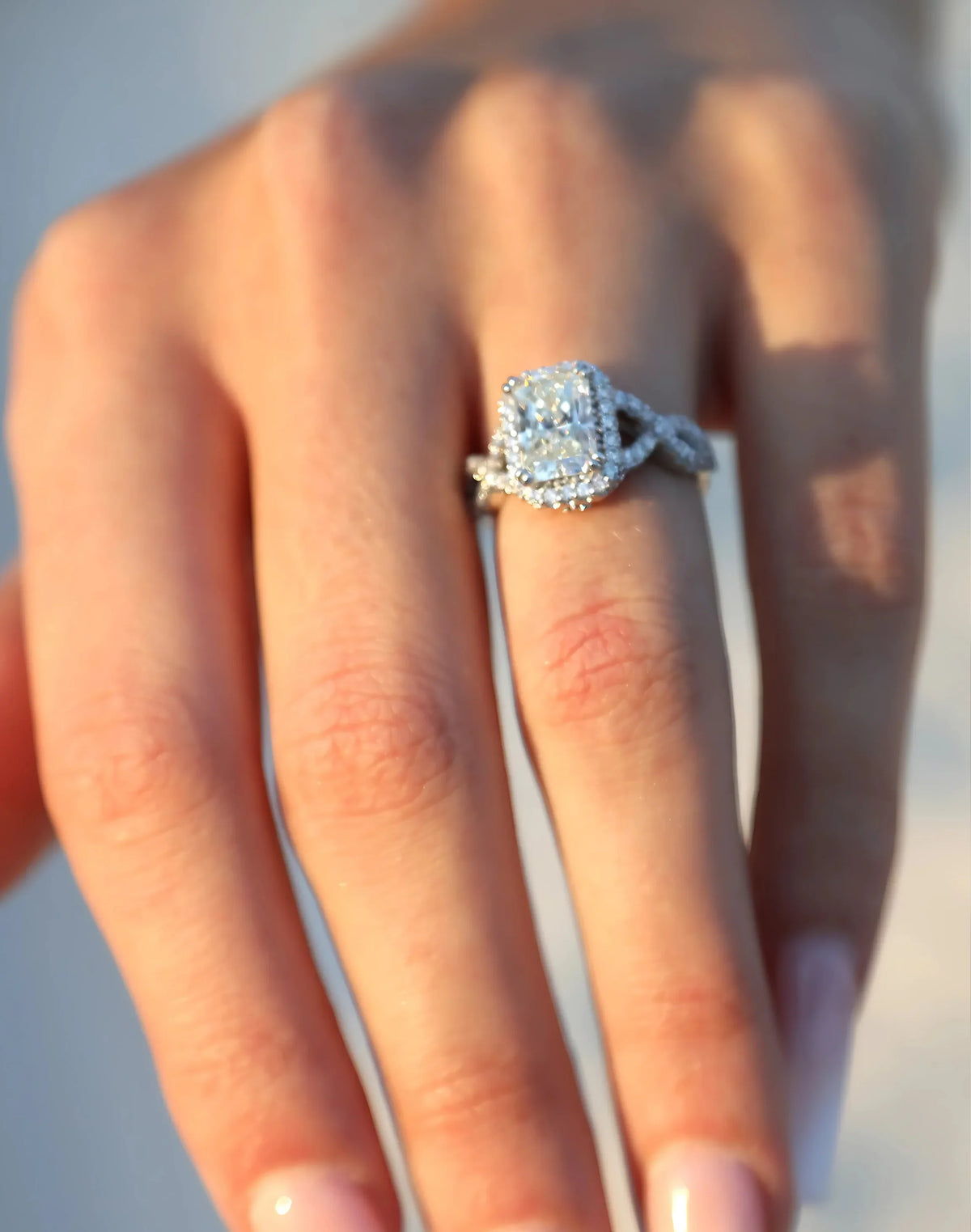 Elegant diamond engagement ring with halo design on finger, showcasing brilliance and craftsmanship.