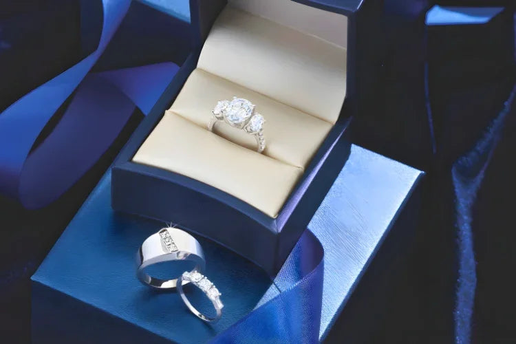 Elegant diamond engagement ring with side stones in luxury box, paired with matching wedding bands