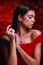 Model wearing the lab-grown ruby and Mozambique garnet collection in 14K yellow gold: dangle earrings, hoop, stackable rings and layered necklaces